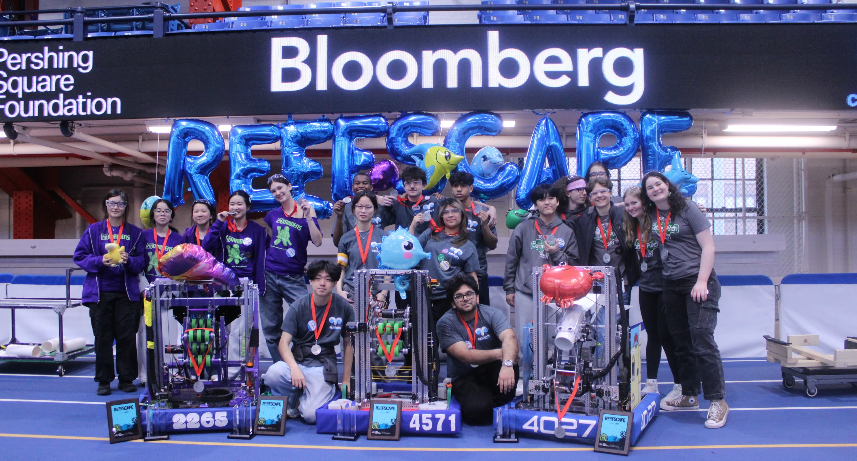 Teams 2265, 4571, and 4027 with their robots and silver finalist medals at the 2025 NYC Regional, in front of REEFSCAPE balloons